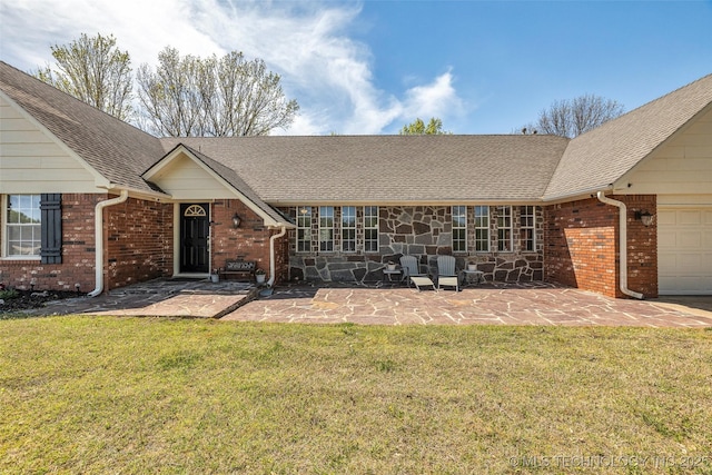 back of property featuring a yard, an attached garage, and brick siding