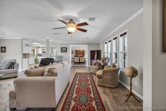 living area with visible vents, baseboards, ornamental molding, ceiling fan, and wood finished floors