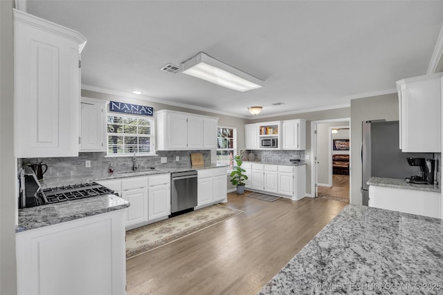 kitchen with stainless steel appliances, visible vents, and ornamental molding
