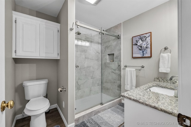 full bath featuring vanity, baseboards, toilet, a shower stall, and wood finished floors