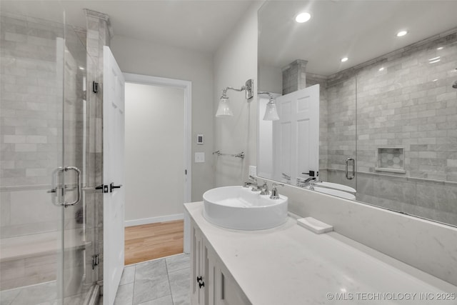 bathroom with a shower stall, vanity, baseboards, and recessed lighting