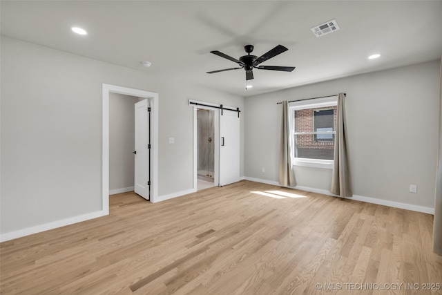unfurnished bedroom featuring visible vents, recessed lighting, a barn door, light wood finished floors, and baseboards