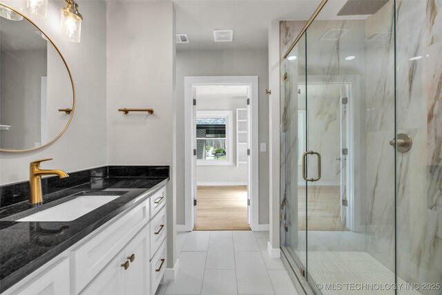 bathroom featuring vanity, baseboards, tile patterned floors, a marble finish shower, and visible vents