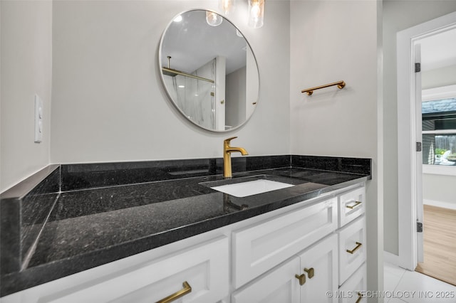 bathroom with vanity, baseboards, and walk in shower