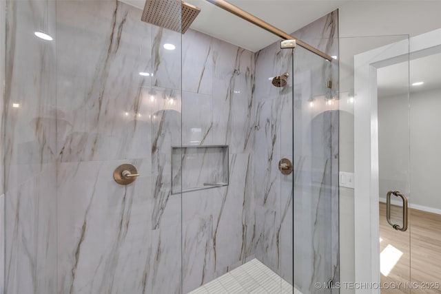 full bathroom with a marble finish shower and wood finished floors