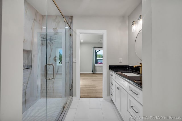 full bathroom with tile patterned floors, vanity, baseboards, and a marble finish shower