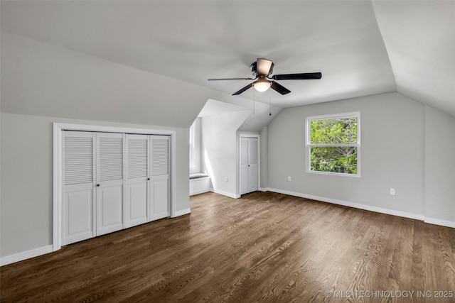 additional living space featuring ceiling fan, dark wood-style floors, baseboards, and lofted ceiling