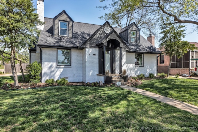 view of front of house featuring brick siding, a front lawn, and a chimney
