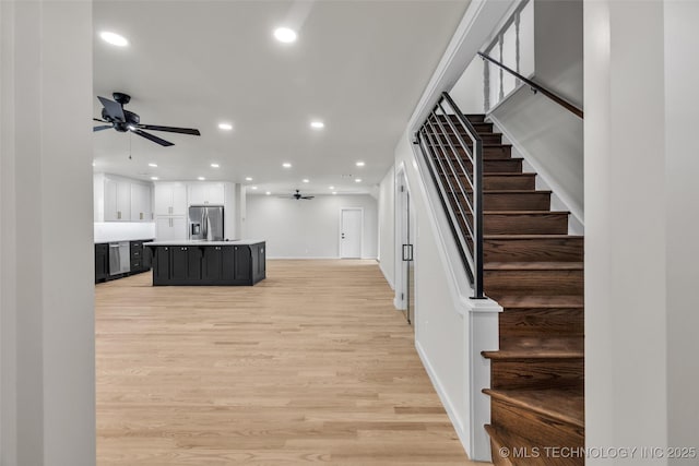 interior space featuring stainless steel fridge with ice dispenser, dark cabinets, recessed lighting, light wood-style flooring, and ceiling fan