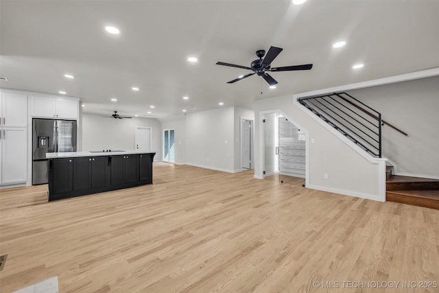 unfurnished living room with light wood-style floors, recessed lighting, a ceiling fan, and stairway