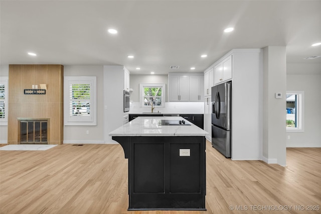kitchen with white cabinets, light stone countertops, recessed lighting, and refrigerator with ice dispenser