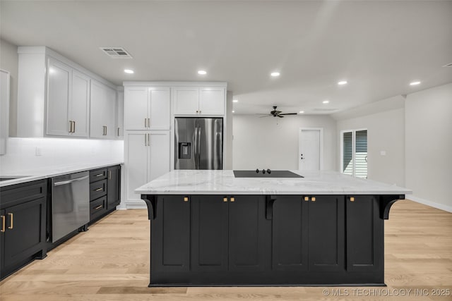 kitchen with a kitchen island, white cabinets, visible vents, a kitchen bar, and stainless steel appliances