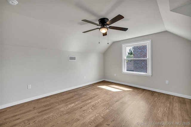 additional living space featuring visible vents, baseboards, ceiling fan, wood finished floors, and vaulted ceiling