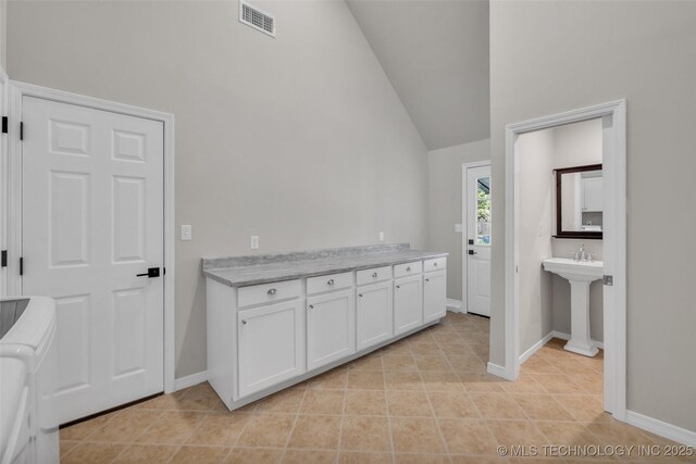 kitchen with white cabinets, visible vents, and baseboards