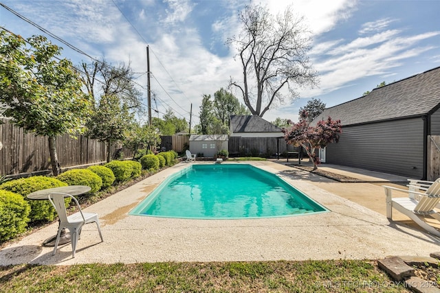 view of pool with a shed, a fenced backyard, an outdoor structure, a patio area, and a fenced in pool