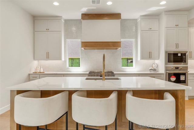 17822 E Patriot Dr, Owasso, OK 74055 - kitchen with stainless steel oven, built in microwave, a center island with sink, tasteful backsplash, and recessed lighting