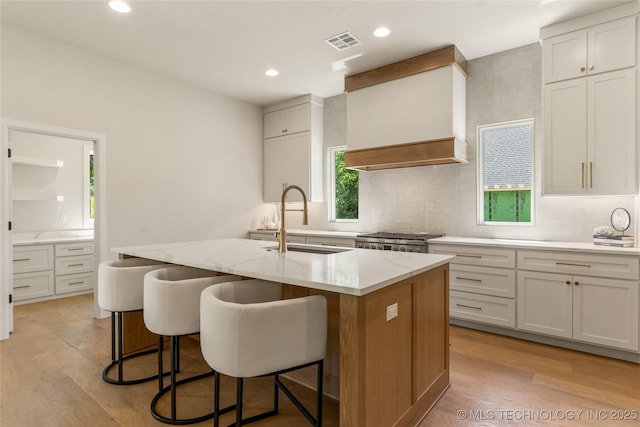 17822 E Patriot Dr, Owasso, OK 74055 - kitchen featuring backsplash, light wood-style floors, a center island with sink, range, and recessed lighting
