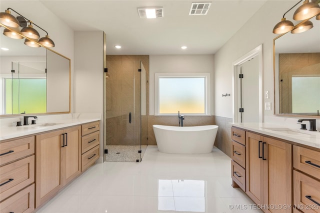 17822 E Patriot Dr, Owasso, OK 74055 - full bath featuring a stall shower, two vanities, a freestanding tub, tile patterned flooring, and tile walls