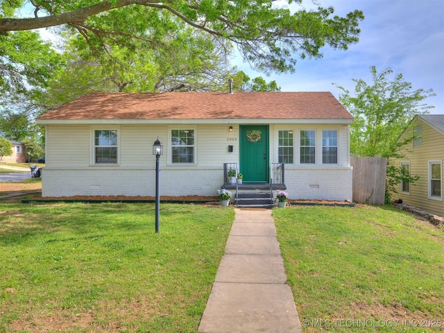 view of front of house with brick siding, a front lawn, crawl space, and fence