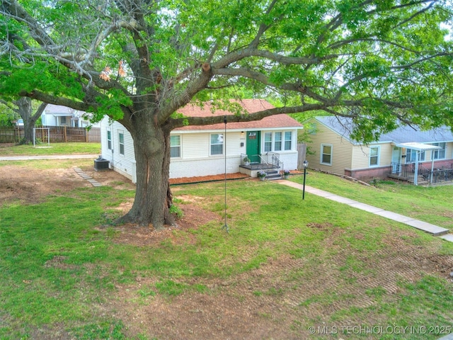 view of front of home featuring central AC unit, fence, and a front yard