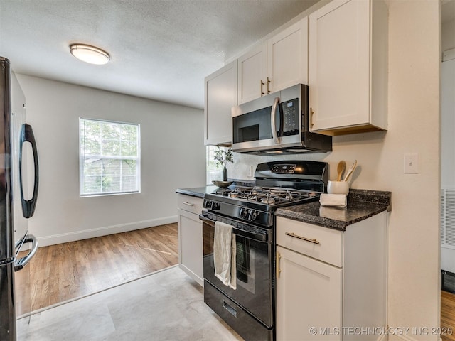 kitchen with dark stone countertops, baseboards, black appliances, a textured ceiling, and white cabinetry