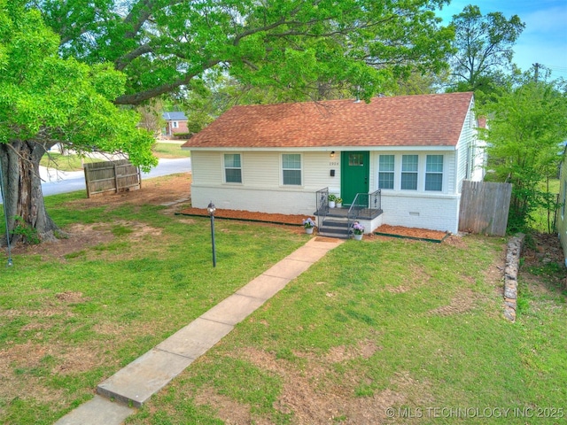 bungalow with fence, a front lawn, brick siding, and roof with shingles