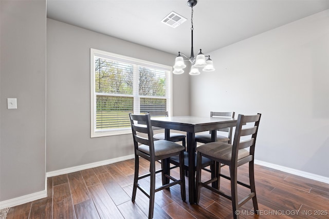 dining space with a chandelier, dark wood-style flooring, baseboards, and visible vents
