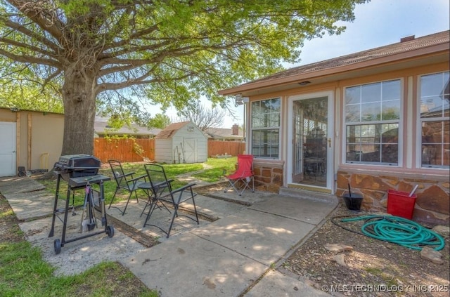 view of patio / terrace featuring a storage shed, grilling area, an outbuilding, and fence