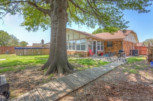 back of house with a fenced backyard, central AC, board and batten siding, a patio area, and stone siding