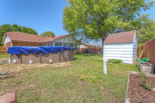 view of yard featuring a fenced in pool, a fenced backyard, a storage unit, and an outbuilding