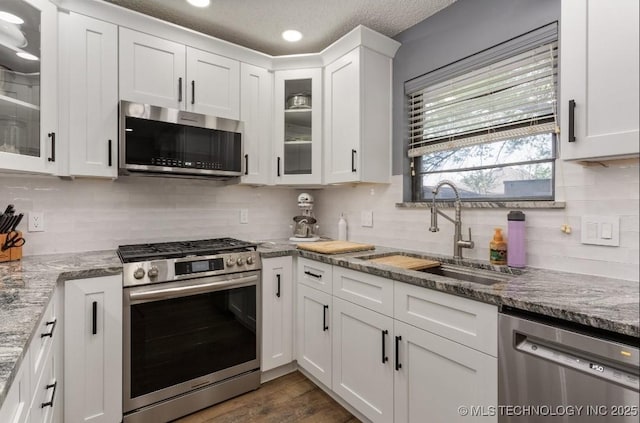 kitchen with white cabinets, backsplash, appliances with stainless steel finishes, and a sink