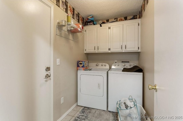laundry area featuring a textured ceiling, baseboards, separate washer and dryer, cabinet space, and light tile patterned floors