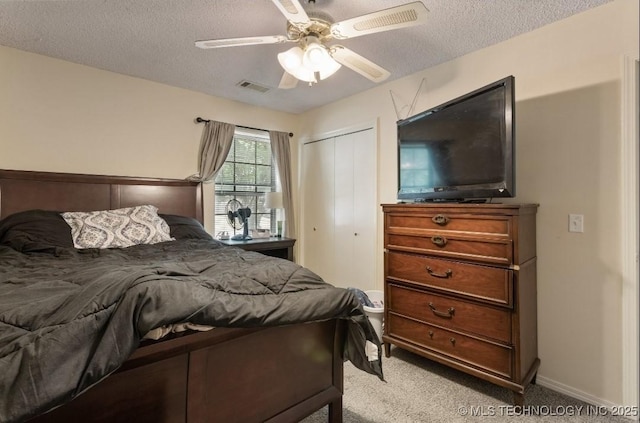 carpeted bedroom featuring a textured ceiling, a closet, ceiling fan, baseboards, and visible vents