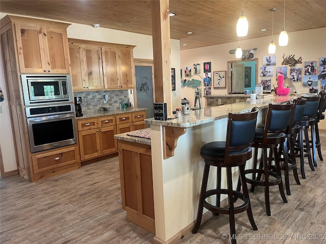 107349 S 4091st Rd, Checotah, OK 74426 - kitchen featuring a breakfast bar area, light wood-style flooring, appliances with stainless steel finishes, and tasteful backsplash