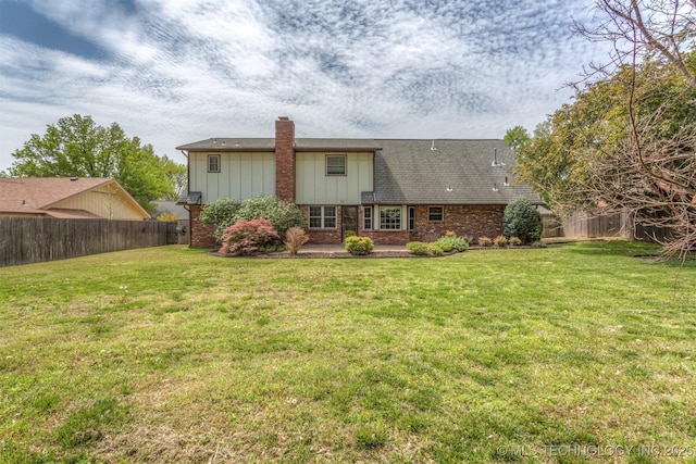 rear view of property with a chimney, fence, a lawn, board and batten siding, and brick siding