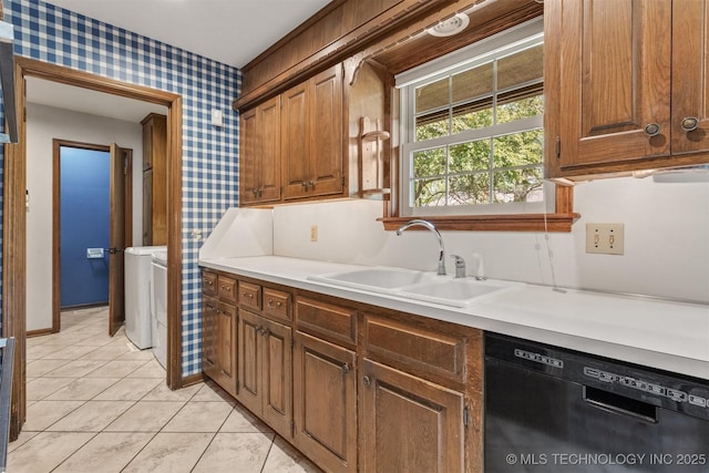 kitchen with light countertops, a sink, wallpapered walls, black dishwasher, and independent washer and dryer