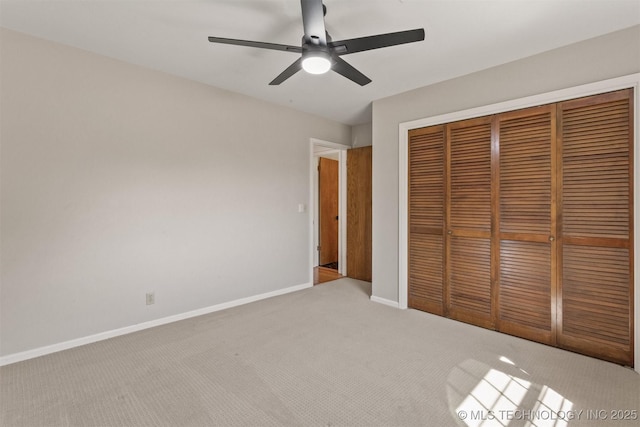 unfurnished bedroom featuring baseboards, a closet, a ceiling fan, and light colored carpet