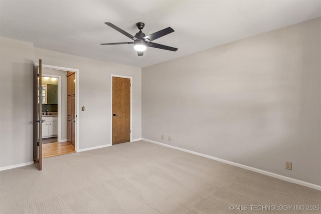 unfurnished bedroom featuring light colored carpet, ensuite bath, and baseboards