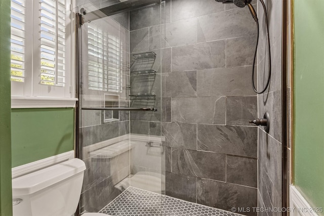 bathroom featuring toilet and a tile shower