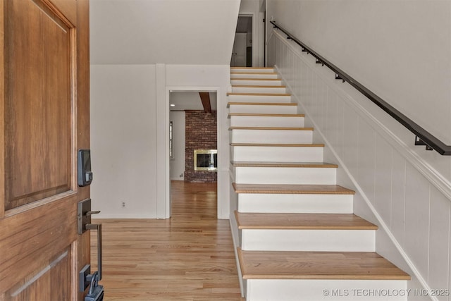 interior space with stairs, light wood-style floors, and a brick fireplace