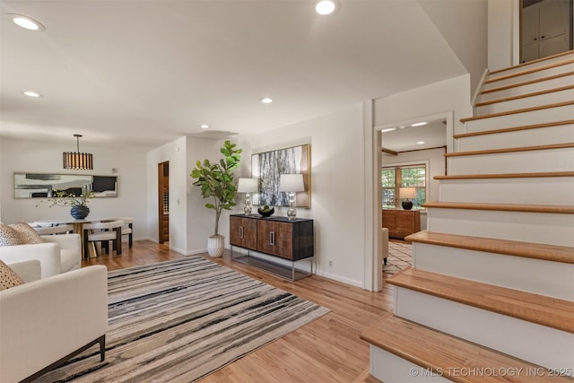 living room featuring light wood finished floors, stairway, baseboards, and recessed lighting