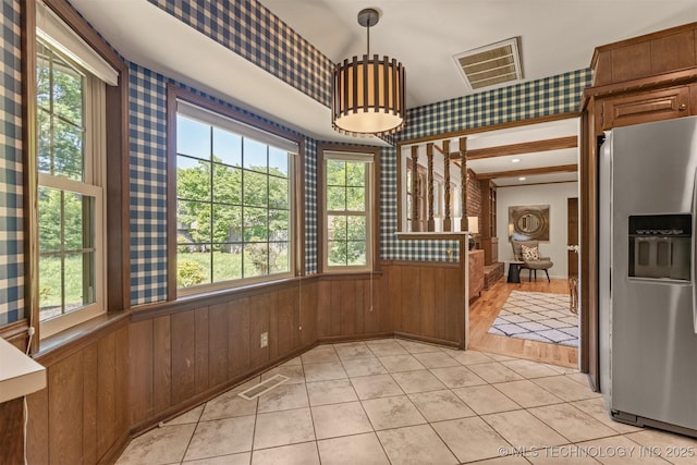 unfurnished dining area with wooden walls, visible vents, and wallpapered walls