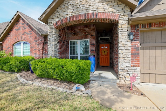doorway to property with brick siding, stone siding, and a garage