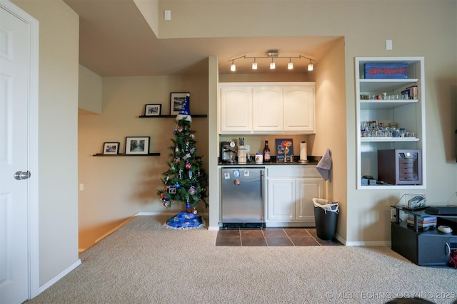 bar with refrigerator, baseboards, a bar, and dark carpet