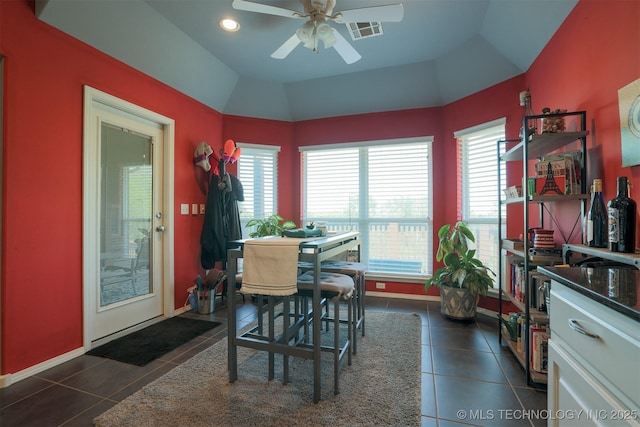 dining room featuring lofted ceiling, visible vents, a ceiling fan, baseboards, and dark tile patterned flooring