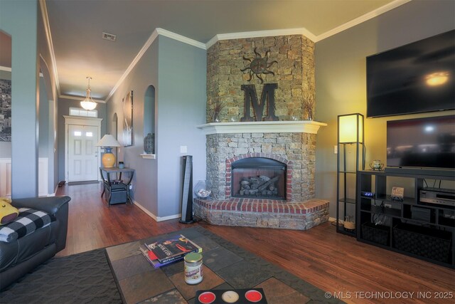 living room with wood finished floors, visible vents, a large fireplace, and ornamental molding