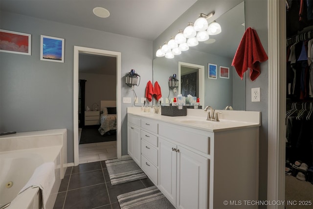 bathroom with tile patterned floors, double vanity, a tub with jets, a sink, and a walk in closet