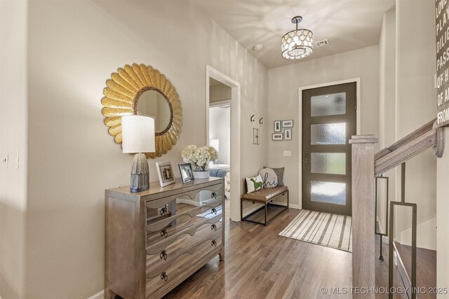 doorway to outside with wood finished floors, baseboards, and a chandelier