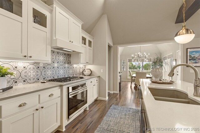 kitchen with appliances with stainless steel finishes, a sink, a chandelier, tasteful backsplash, and light countertops