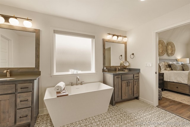 bathroom featuring a freestanding bath, two vanities, and ensuite bath